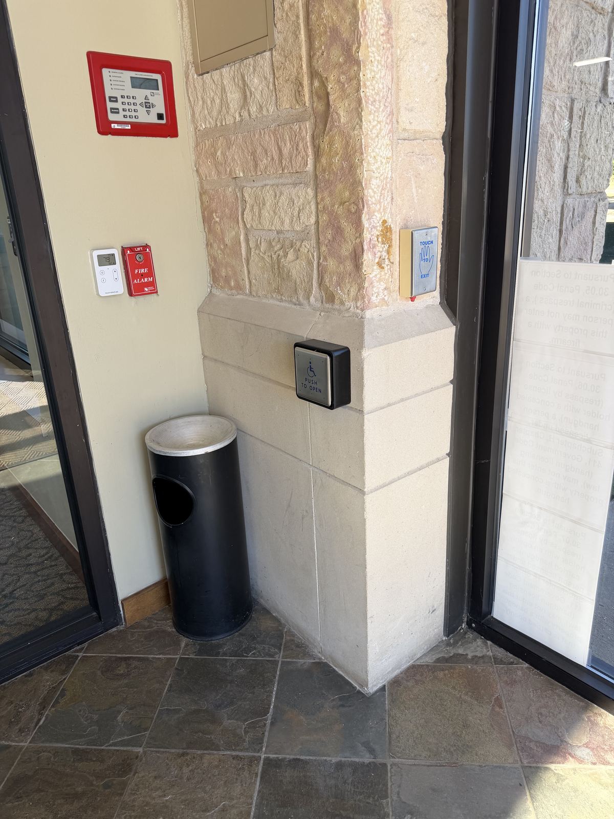 Push button for an automatic door mounted on a stone column inside an entry vestibule