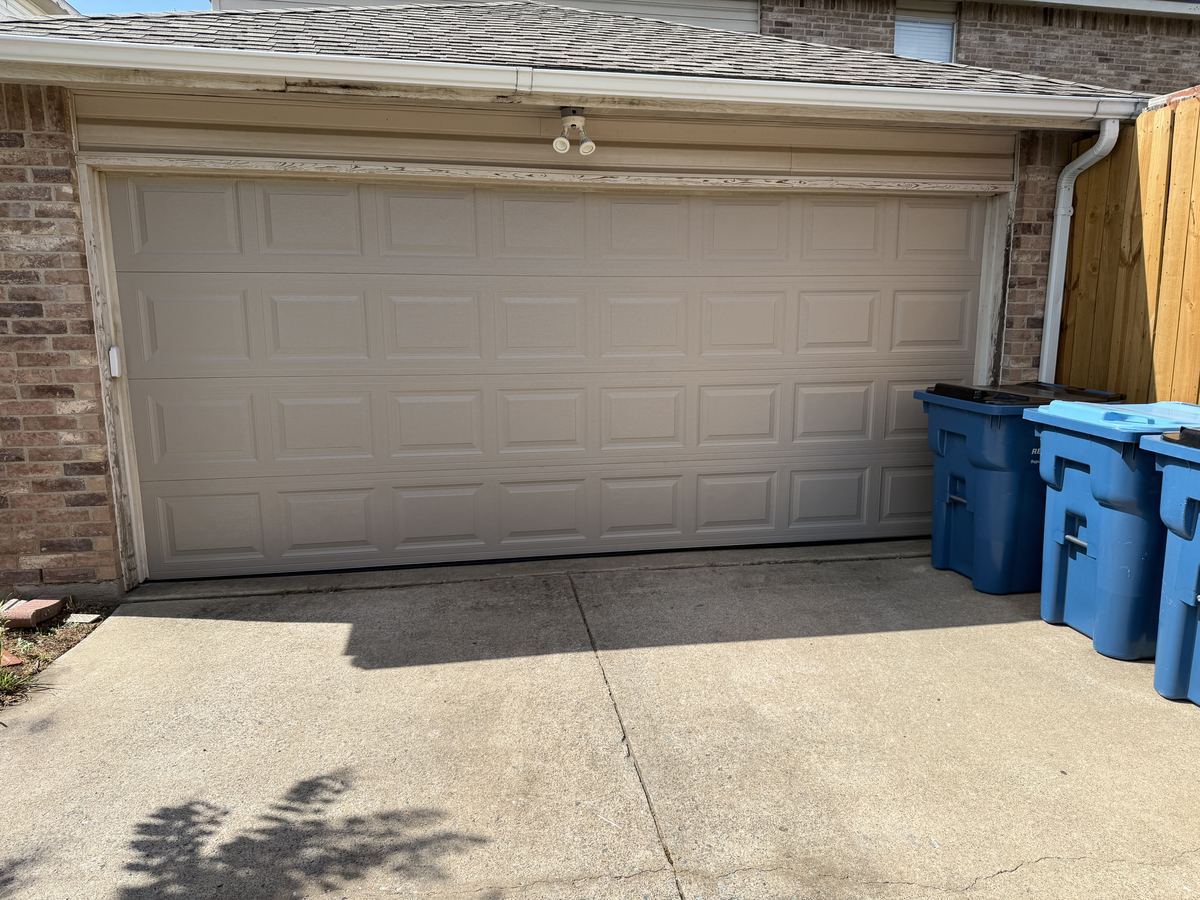 Almond raised-panel double garage door on a brick home