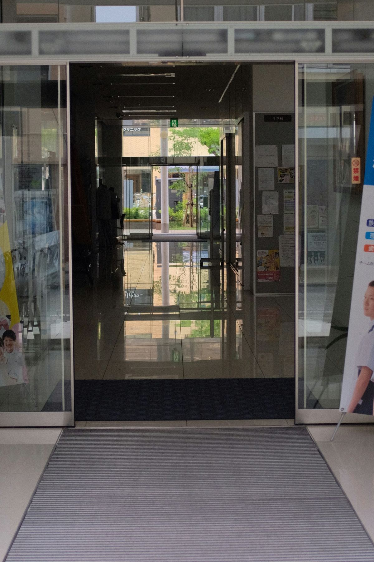 Glass entrance doors and a floor mat inside a building lobby vestibule