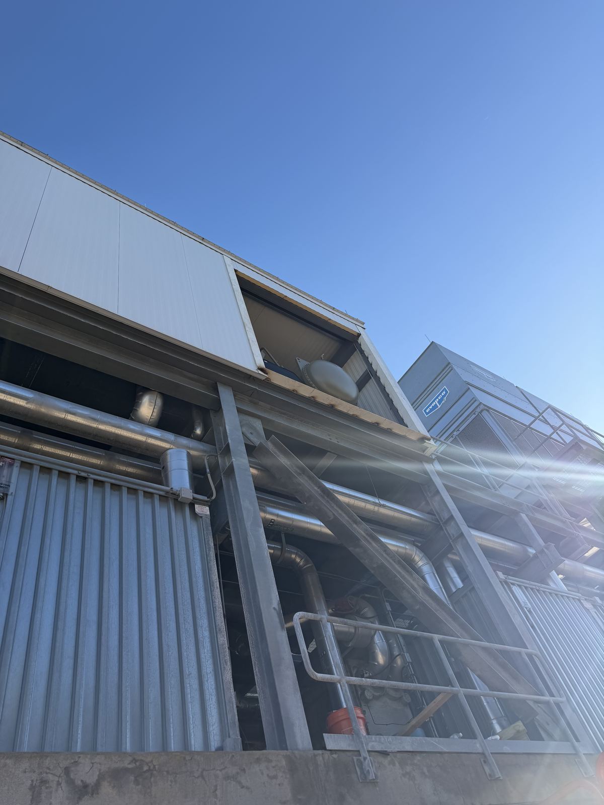 Low view of a raised door opening on an industrial building with steel framing and piping below it