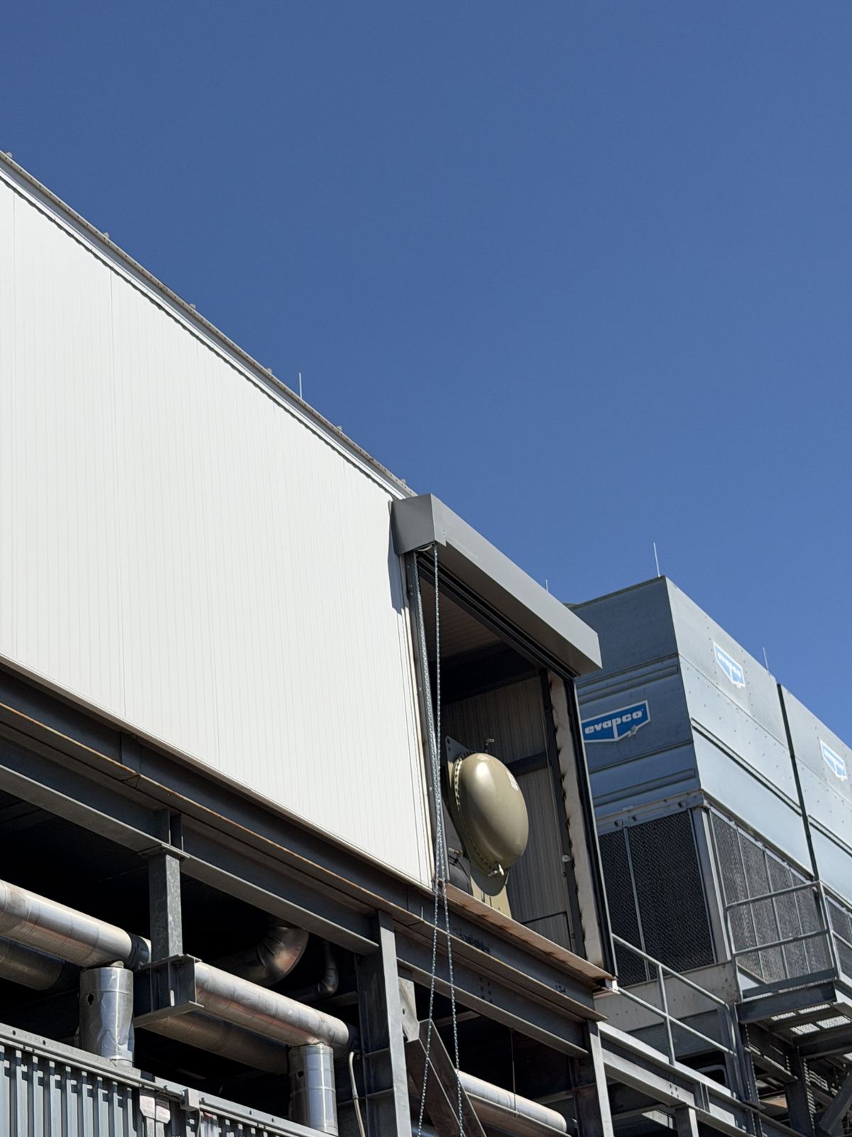 Upper-level door opening on an industrial building with the door hood mounted above it and a hoist chain hanging down