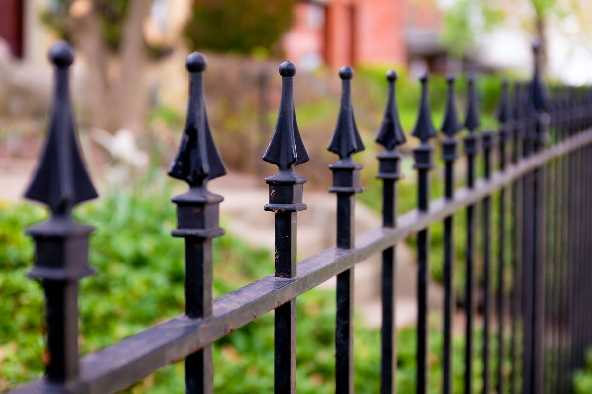 Black iron fence with spear-top pickets beside a lawn
