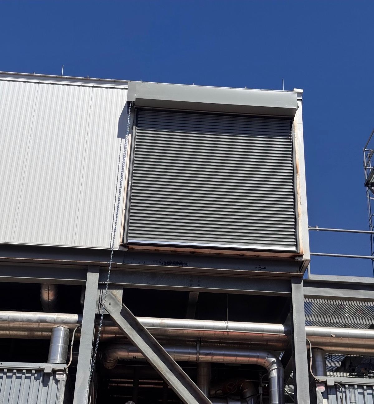 Gray rolling steel door closed in a raised opening on an industrial building