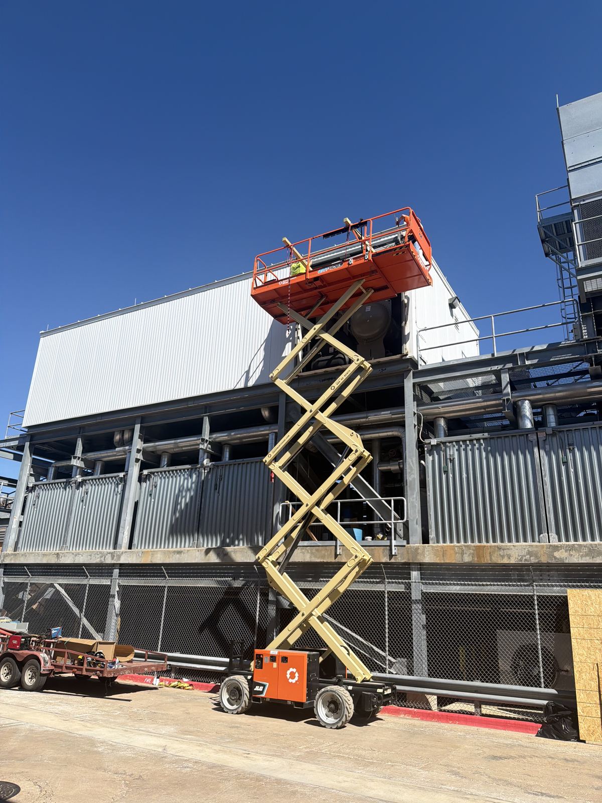 Scissor lift raised to a door opening on the upper level of a metal industrial building