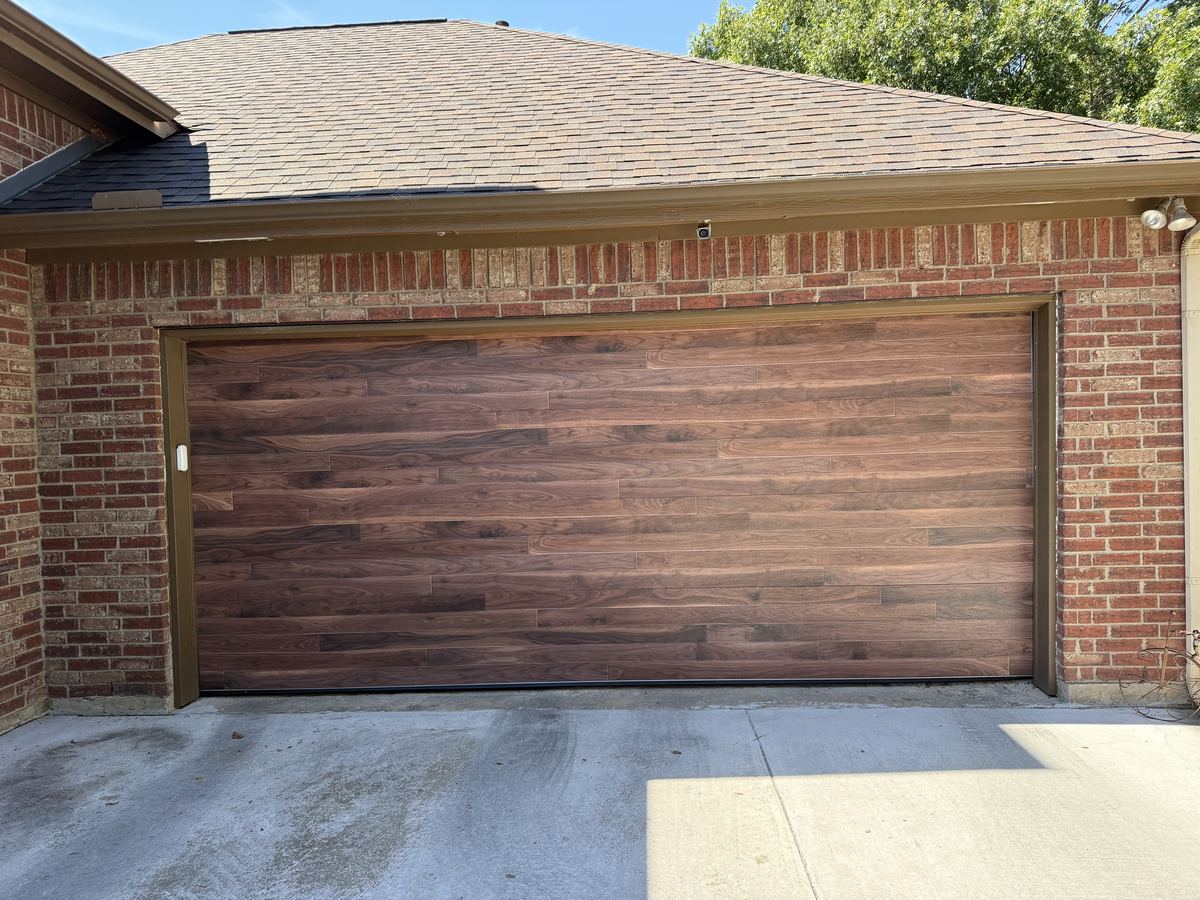 Dark wood-look garage door with horizontal planks on a red brick home